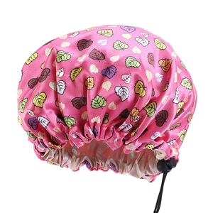 Detail der rosa Satin-Schlafmütze für Babys mit buntem Blattmuster und verstellbarer Schnalle