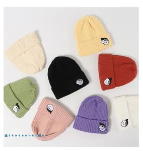 Flat lay of colorful knit beanies for children showing embroidery and eight vibrant colors