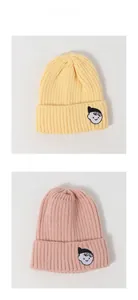 Detail of soft knit beanie with cartoon embroidery patch in yellow and pink color