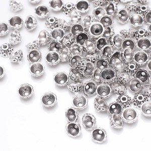 Vintage silver flower bead caps for DIY jewelry making with embossed patterns on white backdrop