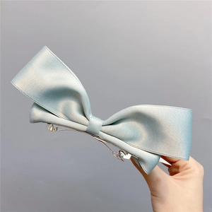 Detail of light blue satin ribbon bow hair clip with silver metal spring clip fastener