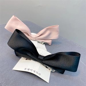 Detail showing pink and black satin bow hair clips with silver metal clips on card
