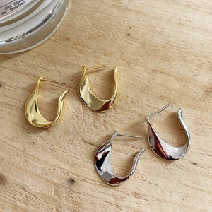 Macro view of gold and silver U-shaped polished sterling silver earrings on wood