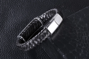 Macro shot of black woven leather texture and polished stainless steel clasp on mens bracelet