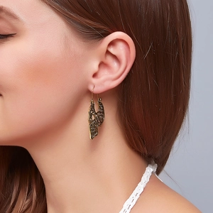 Close-up of gothic vintage hollow carved wing earrings in antique gold on a model