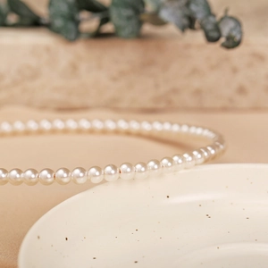 Macro detail of glossy white pearls on a vintage headband with a warm aesthetic