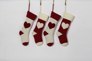 Close-up of 4 knitted Christmas stockings with 3D heart patterns in red and ivory colors