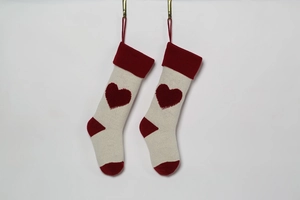 Detail view of knitted Christmas stockings with 3D red heart pattern and red heel accents