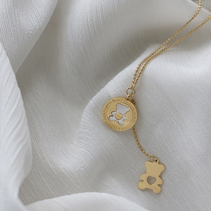 Detail of rose gold bear necklace with mother of pearl and engraved round coin pendant