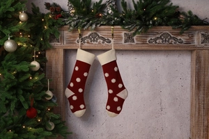 Détail de chaussettes de Noël en tricot à pois 3D rouges et blancs sur une cheminée