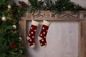 Détail de chaussettes de Noël rouges tricotées avec pois blancs 3D sur cheminée festive