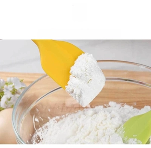 Close-up of heat-resistant silicone spatula mixing flour in a warm baking scene