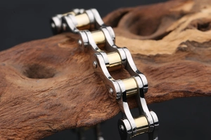 Close-up of gold and silver motorcycle chain bracelet on rustic wood background