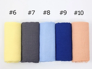 Close-up of lightweight pleated cotton linen scarves in various colors with frayed edges