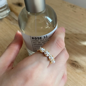 Close-up of gold flower ring featuring white pearls and marquise-cut zircons on hand