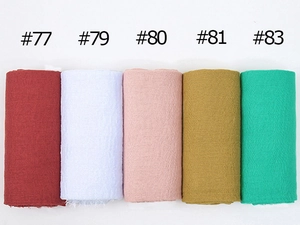 Detail view of colorful crinkled cotton scarves showing burgundy, pink, yellow, and green textures