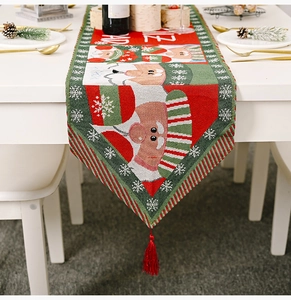Detailed view of red and green knitted Christmas table runner with tassels and Merry text
