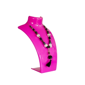Dettaglio collana di perline con nappa su supporto manichino rosa e sfondo bianco puro