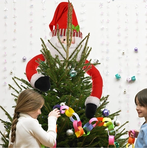 Detail of plush Santa Claus tree topper with long arms hugging a decorated Christmas tree