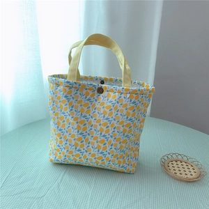 Floral canvas lunch bag with yellow flower prints and sturdy handles on checkered cloth