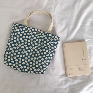 Detailed view of dark blue floral canvas tote bag with white petals and bronze button