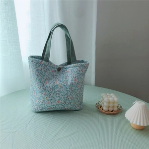 Close-up of floral cotton tote bag with vintage blue patterns and green handles