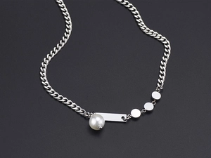 Detail of silver pearl pendant necklace with rectangular metal tags on black background