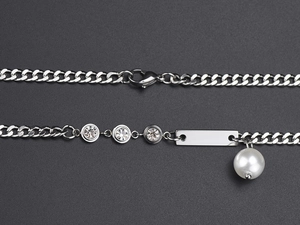 Detailed shot of silver Cuban chain with zirconia accents, bar charm, and pearl pendant
