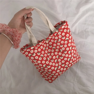 Detail of red floral canvas handbag with white flower pattern and white strap handles