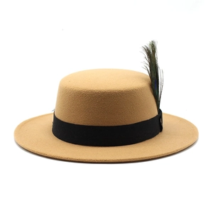 Detail of camel wool boater hat featuring a black ribbon and natural peacock feather accent