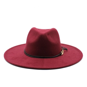 Detail of burgundy wool fedora hat with a thin black leather band and gold metal buckle