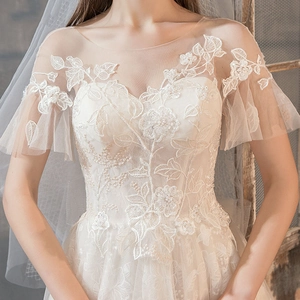 Elegant white French lace wedding dress with sheer neckline and floral embroidery