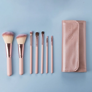 Detailed view of a 7-piece pink makeup brush set with a rose gold pouch on blue background