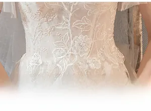 Detail of waist design on white lace wedding dress with floral sequin embroidery