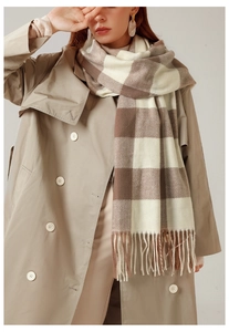 Dettaglio della sciarpa scozzese marrone e beige con frange su un trench coat kaki
