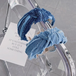 Détail de la texture denim effilochée et du nœud sur des serre-têtes larges et tendance