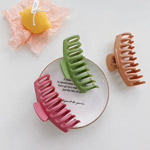 Three matte large hair claws in pink, green and brown colors on a white background