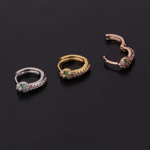 Three snake-shaped hoop earrings in gold, silver, and rose gold with green stone eyes