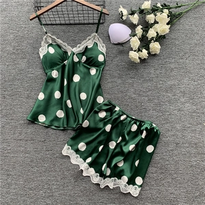 Detail of dark green satin pajama set with white polka dots and lace trim on the hanger