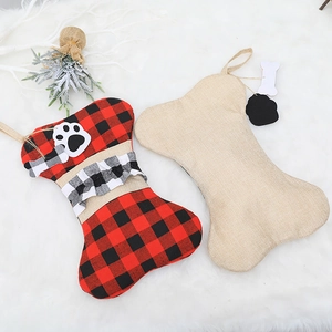 Set of two bone-shaped linen Christmas stockings with buffalo plaid and paw tags on plush rug