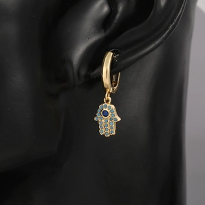 Detail of gold Hamsa hand earring with blue zircon Evil Eye hanging on model