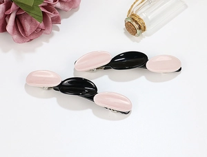Detail of pink and black acetate hair clips with triple oval geometric wave design