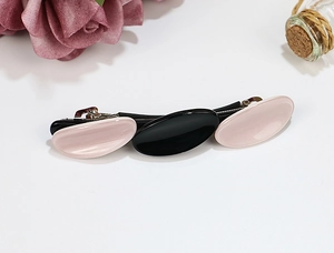 Close-up of a three-piece acetate hair clip featuring pink and black oval geometric designs