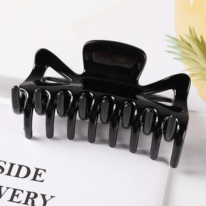 Detailed close-up of a large glossy black geometric hair claw clip on a stylish book