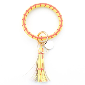 Detail of yellow baseball-style leather bangle keychain with tassel and gold hardware