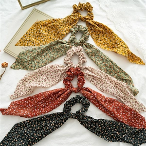 Flat lay of five floral ponytail scrunchies in yellow green beige red and black colors
