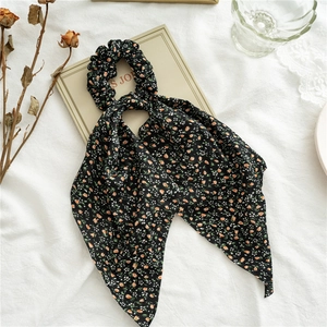 Close-up of black floral ponytail scrunchie with orange flower print and matching ribbon scarf