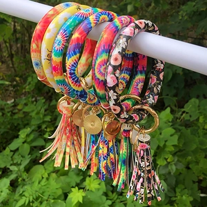 Close-up of tie-dye and floral PU leather ring keychains with matching tassels