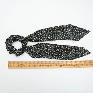 Black floral scrunchie with long ribbons and measuring ruler on white background