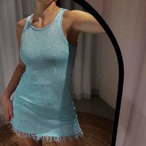 Detail of light blue knit bodycon dress with shimmering metallic yarn and fringe hem